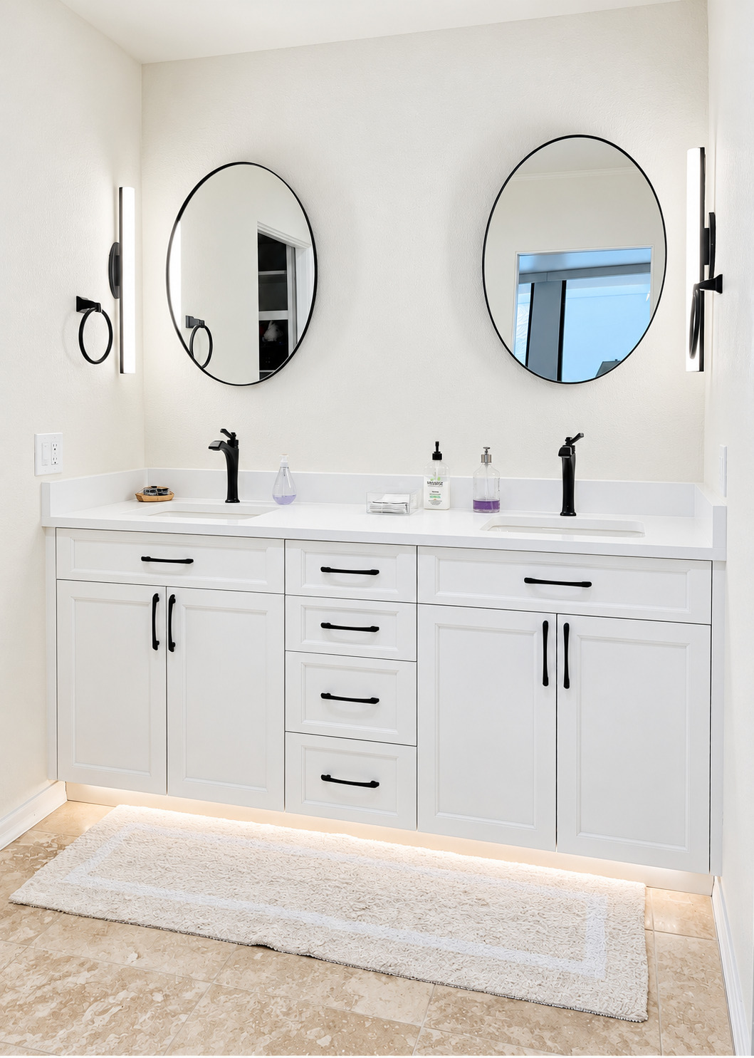 White double vanity with two round mirrors and illuminated wall lights