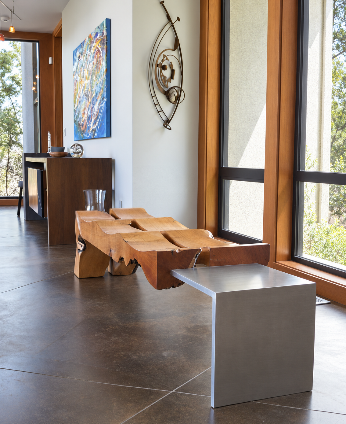 Sculptural wood entry bench viewed from the opposite end with its long metal support visible